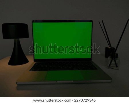 This stock photo features a modern laptop with a blank green screen displayed on a poplar wood desk, providing an ideal workspace for remote work, technology, productivity, and creativity. The minimal