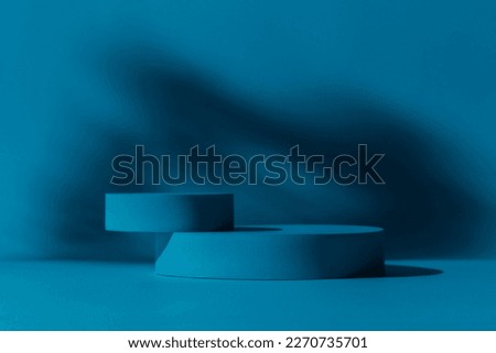 Blue round stage, podium and leaves shadows on dark blue background. Stylish and minimalist product display.