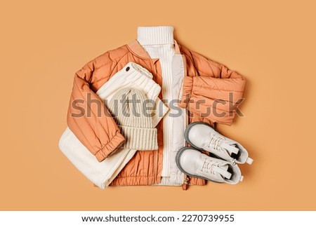 Stylish terracotta children's autumn jacket with knitted sweater, trousers and boots. Fashion kids outfit for for spring, autumn or winter. Flat lay, top view Royalty-Free Stock Photo #2270739955