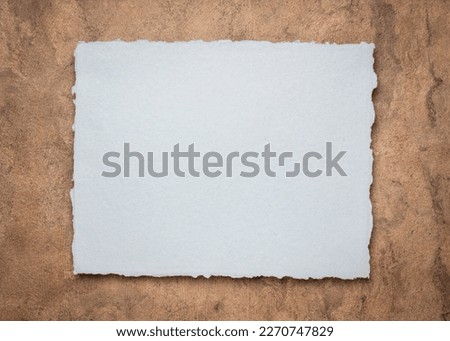 gray and brown abstract - a sheet of blank Indian handmade rag paper against textured bark paper, copy space Royalty-Free Stock Photo #2270747829