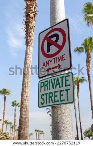 Close up view of no parking street sign on sunny summer street with palms