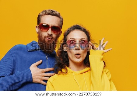 Man and woman couple smiling cheerfully and crooked with glasses, on yellow background, symbols signs and hand gestures, family shoot, newlyweds.