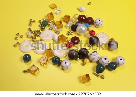 handmade beaded jewelry and multi-colored beads on a yellow background