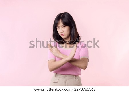 portrait young serious asian woman with cross arm gesture showing stop, no, wrong, denial, rejection sign isolated on pink pastel studio background. deny and negative expression symbol concept. Royalty-Free Stock Photo #2270765369