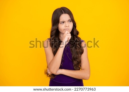 Angry teenager girl, upset and unhappy negative emotion. Smart nerdy school girl touching cheek and thinking against yellow background. Child think and idea concept.