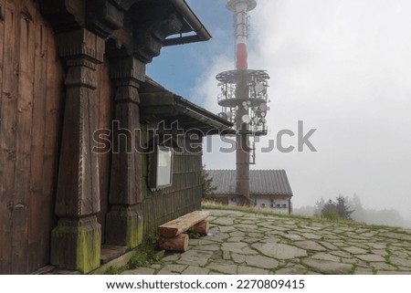 Wooden chapel , on background radio and televison transmitter on summer foggy day in Beskid  mountains in Czech Republic 