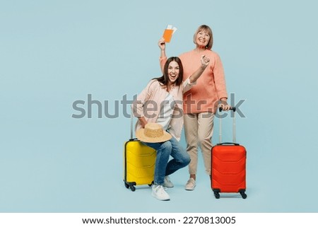 Elder parent mom with young daughter two women in casual clothes hold passport ticket valise isolated on plain blue background Tourist travel abroad in free time rest getaway. Air flight trip concept Royalty-Free Stock Photo #2270813005