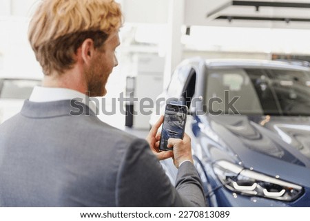 Man customer male buyer client in classic suit take photo of car on mobile cell phone choose auto want buy new automobile in car showroom vehicle salon dealership store motor show indoor Sales concept