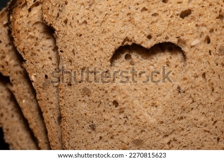 Background, detail and close-up shot of a few slices of German wholemeal bread, one on top of the other. A hole was cut in the center in the shape of a heart Royalty-Free Stock Photo #2270815623