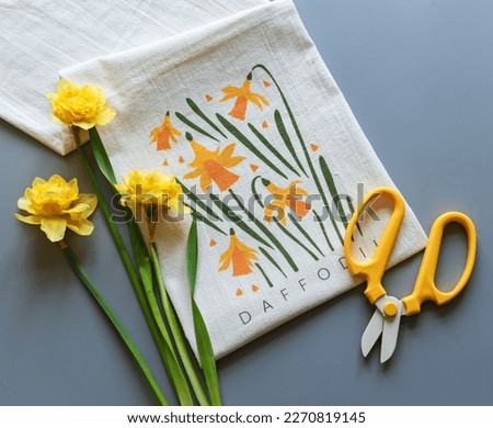 Nacissus on a towel with daffodils print and yellow scissors