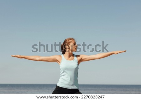 Virabhadrasana, woman in sportswear do sports fitness and yoga on seashore. athletic millennial female trains before marathon, healthy lifestyle, love for her body, mental and physical condition,  Royalty-Free Stock Photo #2270823247