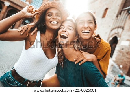 Three multiracial young women having fun walking on city street - Happy girlfriends hanging outside on a sunny day - Different females laughing together outside - Life style and friendship concept Royalty-Free Stock Photo #2270825001
