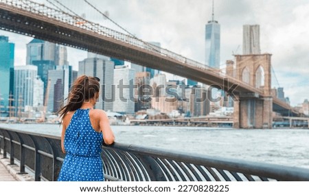 New York City woman looking at Brooklyn Bridge and view of downtown Manhattan skyline from Brooklyn park living urban lifestyle during summer travel in New York City, USA