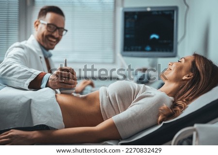 Doctor makes the patient women abdominal ultrasound. Ultrasound Scanner in the hands of a doctor. Diagnostics. Sonography. Close-up Of Doctor Moving Ultrasound Probe On Pregnant Woman's Stomach