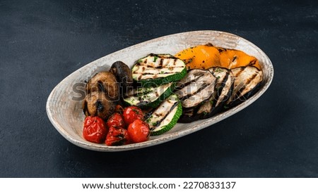 Grilled vegetables in plate. Garnish grilled eggplant, zucchini, cherry tomatoes, mushrooms and bell peppers. Royalty-Free Stock Photo #2270833137