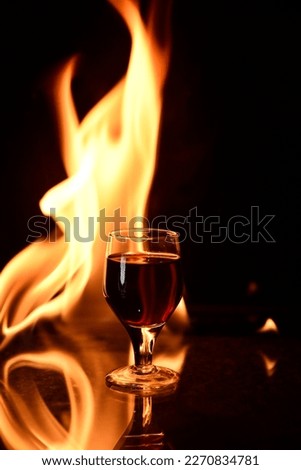 shot of cognac drink with fire in the background glass of red wine