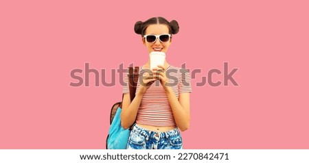 Portrait of happy smiling young woman drinking coffee with cool hairstyle wearing backpack on pink background