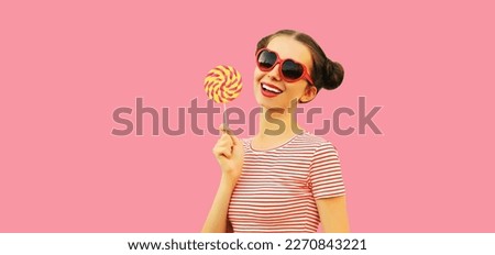 Summer portrait of happy smiling young woman with colorful lollipop wearing red heart shaped sunglasses on pink background