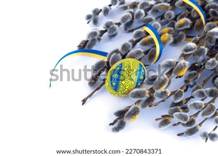 traditional Ukrainian Easter egg in national colors, twigs of willow  and a yellow-blue ribbon on a white background Royalty-Free Stock Photo #2270843371
