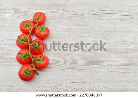 Truss tomatoes standing on the left side of a wooden table