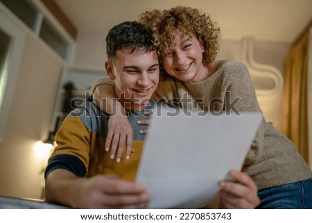 Young man male student teenager and his mother celebrate scholarship read mail letter happy exited smiling reading entry test results success celebrating achievement concept copy space real people Royalty-Free Stock Photo #2270853743