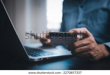 Hand holding credit card for makes a purchase on the Internet on the laptop computer with credit card, online payment, shopping online, e-commerce, internet banking, spending money concept.