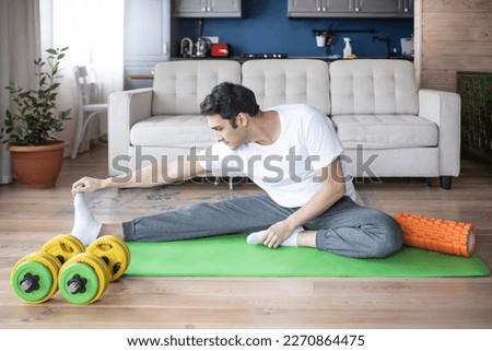 Young handsome man in sportswear do exercises at home. Healthy lifestyle and self isolation concept Royalty-Free Stock Photo #2270864475