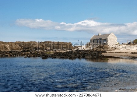 View of the Atlantic shoreline with a solitary house in the distance and waves gently lapping the shore, creating a peaceful and serene atmosphere. Royalty-Free Stock Photo #2270864671