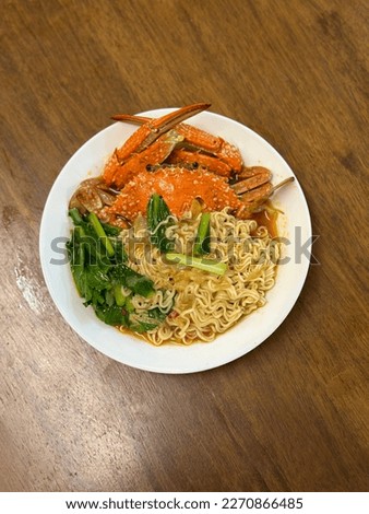 This picture shows an instant noodle with crab and vegetables in it.