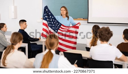 Confident young female professor shows students flag of USA