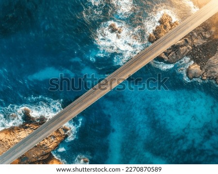 Aerial view of bridge, sea with waves and stones at sunset in Lofoten Islands, Norway. Landscape with beautiful road, transparent blue water, rocks. Top view from drone of highway in summer. Transport Royalty-Free Stock Photo #2270870589