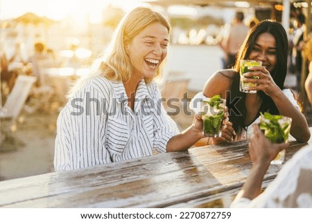 Happy girls having fun drinking cocktails at bar on the beach - Soft focus on left girl face Royalty-Free Stock Photo #2270872759