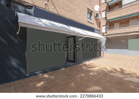 Blue-grey facade of a commercial premises with retracted white awnings at street level