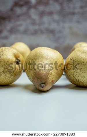 Some ripe pears on the surface of a subtle soft blue color and defocused brick background