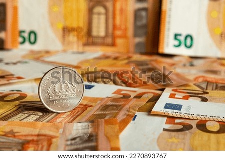One Swedish Krona stands on the background of euro banknotes.  Royalty-Free Stock Photo #2270893767