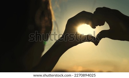 heart sign sunset background. beautiful girl with flowing hair against backdrop sunset sky. love health sign silhouette. Valentine's Day. state mind love. romantic girl glare sun shows heart. concept.
