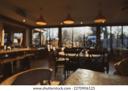 Cosy café interior with warm evening light, relaxing ambience with a selection of wooden tables and warm overhead tungsten lamps creatively blurred Royalty-Free Stock Photo #2270906125