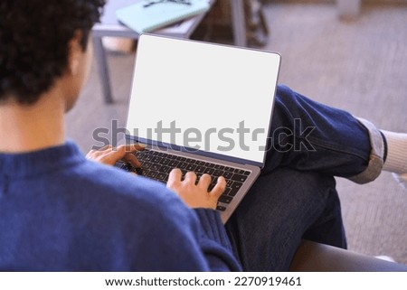 View from the back of businessman or student, freelance entrepreneur, copywriter, journalist using laptop with empty white digital screen with free space for your mobile application or advertising