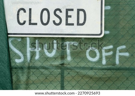 Construction area that says closed shut off on green fabric to cover chained link fence in downtown city streets. Project to build or demolish buildings and structures in suburban areas of town.