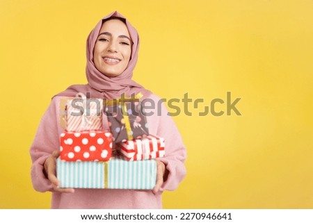 Happy muslim woman with scarf holding many gifts