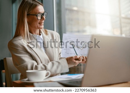 Businesswoman making online videoconference and demonstrate financial graphs to colleagues in cafe