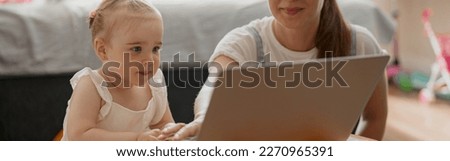 Happy mother and child daughter spending leisure time and watching cartoons on laptop at home