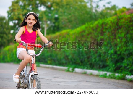 Portrait of cute hispanic girl on bicycle