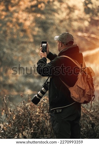 Professional wildlife photographer man taking pictures with digital camera equipment of birds and animals in nature.