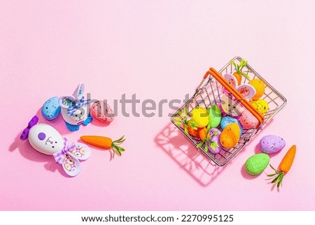 Easter sale concept. Shopping basket with festive symbols - rabbit, eggs, bird, and traditional decor. Pastel design, trendy hard light, dark shadow, pink background, top view