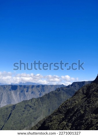 A breathtaking aerial view of the stunning Mafate Cirque in Reunion Island, surrounded by lush green mountains and dotted with small traditional houses. This picture captures the beauty and serenity o
