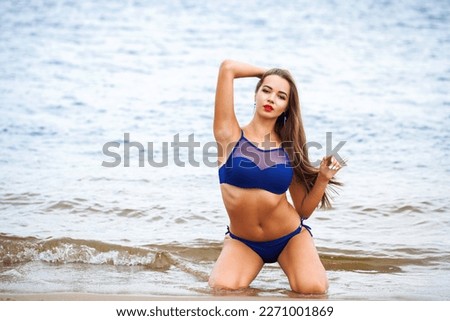 Full body portrait of a young beautiful brunette woman posing in blue bikini