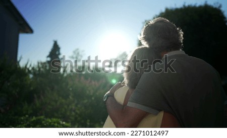 A senior couple standing with arms around each other stands outdoors. Happy married older man and woman hug during sunset Royalty-Free Stock Photo #2271012497