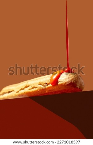 The eclair is poured with orange glaze and sprinkled with pistachios on an orange background. Creative food poster Royalty-Free Stock Photo #2271018597