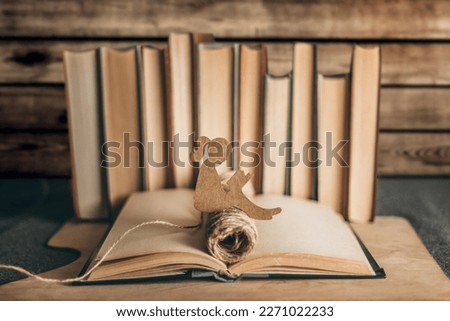 World Knowledge Day. A paper shape of a girl sits on an old book on a wooden background